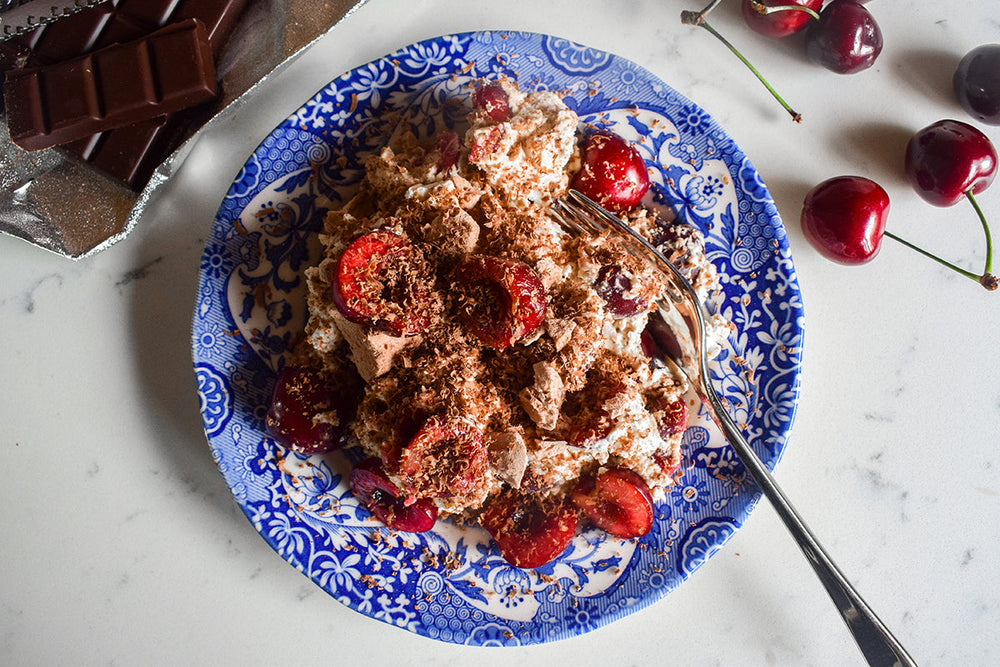 Chocolate shards, whipped cream and fresh halved cherries in an Eton Mess style dessert