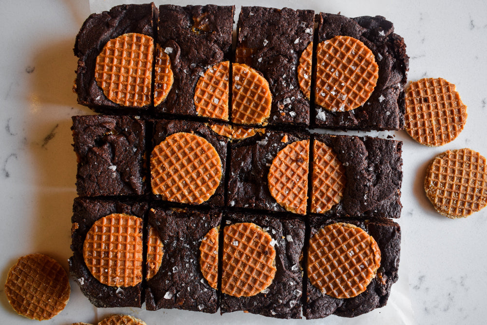 Sheet of chocolate brownies topped with caramel stroopwafel pieces and sliced into individual squares.